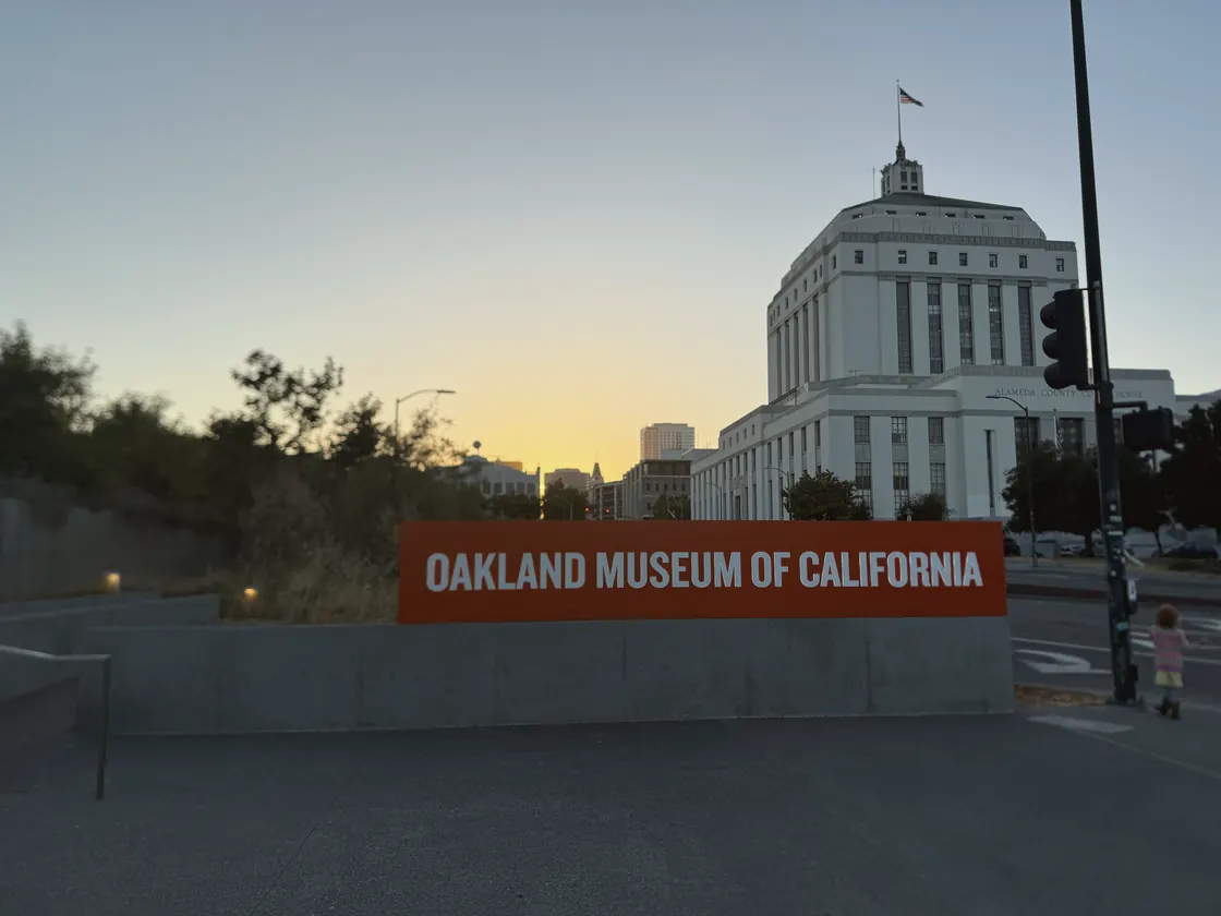 The Oakland Museum of California sign at sunset, the courthouse behind it.