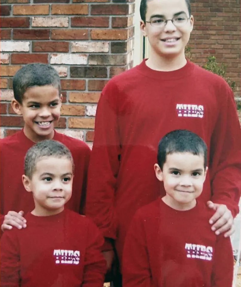 The four of us in matching red school sweatshirts against a brick wall, me tallest at the back in glasses, my arms round the two youngest.