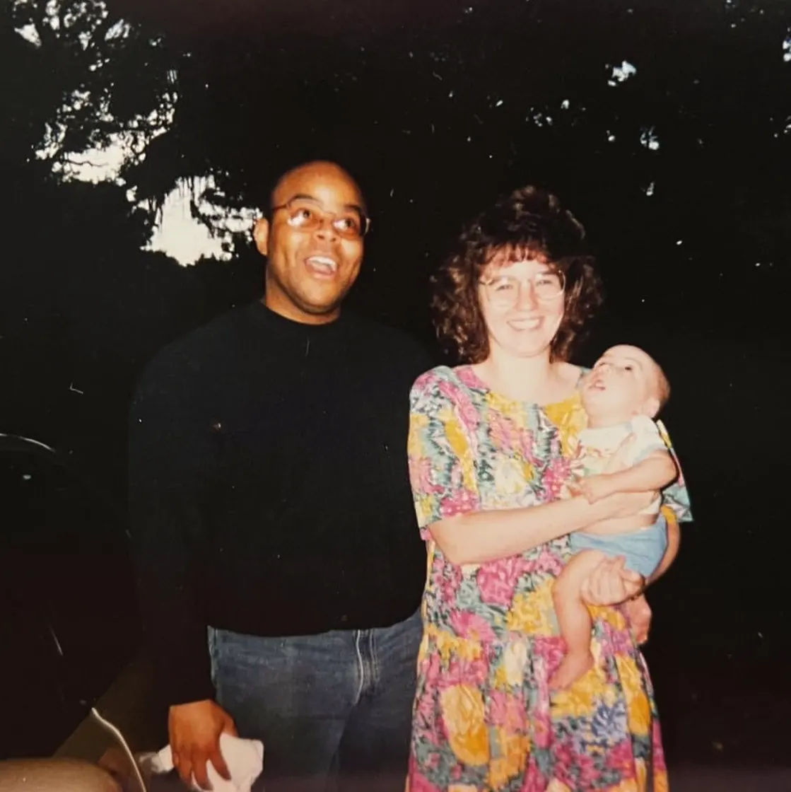 My parents outside at night, my mother holding me as a baby.