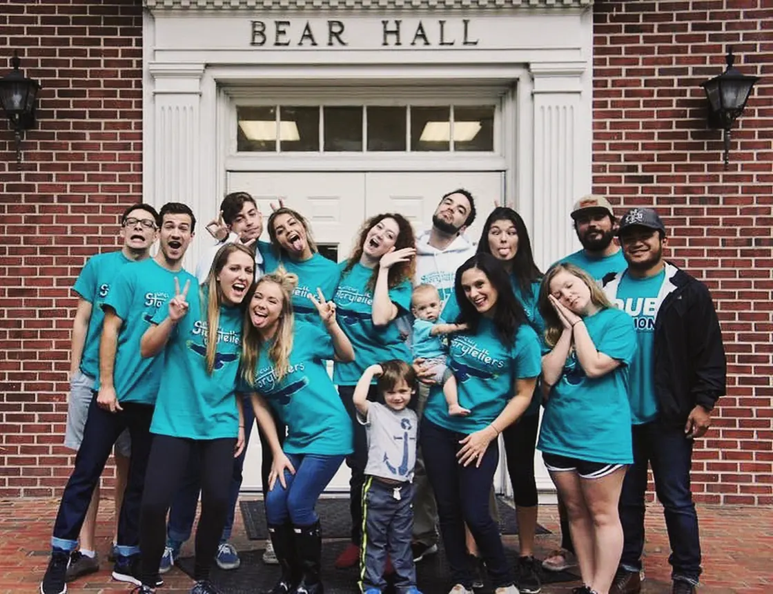 The UNCW Storytellers piled on the steps under the Bear Hall doorway, most in teal Storytellers shirts, two small children among them, me at the back in a white hoodie.